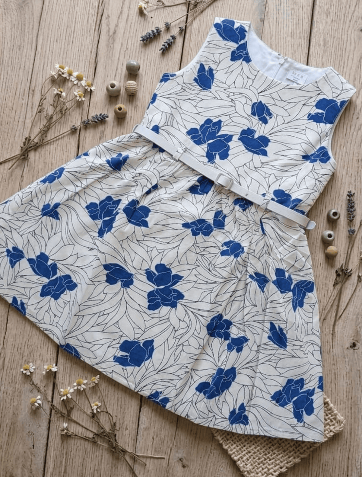 whisperingpoppers summer frocks Floral Cotton Frock with Belt — Vintage Style Girls 1y to 6 Years  blue and white colour floral printed desgin.flat lay detail of the frock  knee length  with silver belt .front view of the frock.perfect for hot summer days in pakistan.wear it on all day long  gatherings.event lunch and dinner.breathable comfortable fabric.imported